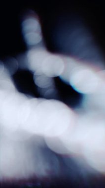 Soft white bokeh lights gently floating in darkness, creating an elegant and dreamy abstract background