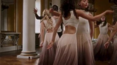 A group of dancers passionately expresses a range of emotions through fluid, synchronized movement in a classical hall