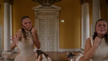 A young dance group delivers a captivating contemporary dance performance with fluid movements and synchronized choreography in an elegant, classical hall