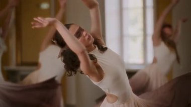 Young female dancers gracefully remove sheer blindfolds during a dynamic dance routine, revealing their expressions as they continue their fluid movements