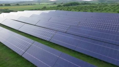 Modern eco-friendly large solar panels to generate energy from suns rays are installed in endless meadows with green grass, under a clear blue sky with bright warm spring sun. UHD 4K video realtime