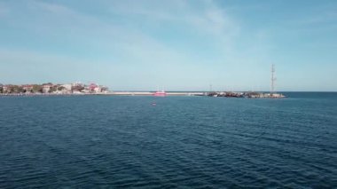 A small sea fishing port with boats in the calm deep cool Black Sea adjoins the ancient resort small town of Pomorie in Bulgaria, under a blue cloudy sky. UHD 4K video realtime