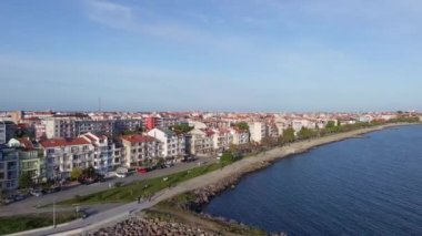 A small sea fishing port with boats in the calm deep cool Black Sea adjoins the ancient resort small town of Pomorie in Bulgaria, under a blue cloudy sky. UHD 4K video realtime