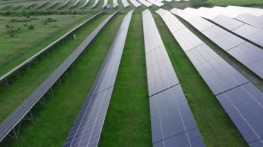Modern eco-friendly large solar panels to generate energy from suns rays are installed in endless meadows with green grass, under a clear blue sky with bright warm spring sun. UHD 4K video realtime