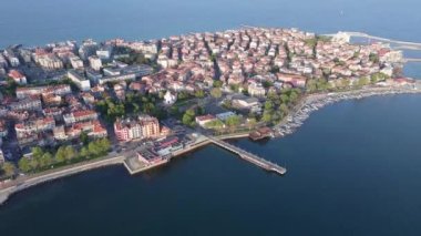 Bulgaristan 'ın kayalık yarımadasında bulunan ve büyük mavi, tuzlu Karadeniz tarafından turlanan küçük ve yoğun nüfuslu Pomorie kasabasına kuş bakışı bir bakış. UHD 4K video gerçek zamanlı