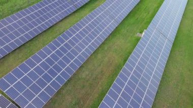 Modern eco-friendly large solar panels to generate energy from suns rays are installed in endless meadows with green grass, under a clear blue sky with bright warm spring sun. UHD 4K video realtime