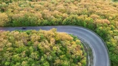 Hızlı modern araba ve kamyonlarla dolambaçlı yeni bir dağ yolu, ufuktaki yeşil yaprak döken ormanlarla Balkan Dağları arasındaki uzaklığa çıkıyor. UHD 4K video gerçek zamanlı