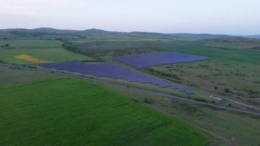 Modern eco-friendly large solar panels to generate energy from suns rays are installed in endless meadows with green grass, under a clear blue sky with bright warm spring sun. UHD 4K video realtime
