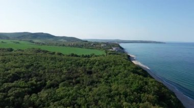 Yaz tatilleri için otelleri ve hanları olan küçük bir tatil köyü yeşil bitki örtüsü ile kayalık ve keskin uçurumlar üzerinde, açık mavi gökyüzüne karşı vahşi Karadeniz üzerinde. UHD 4K video gerçek zamanlı