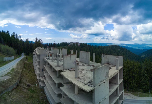 stock image Ruins of unfinished abandoned hotel with concrete walls and several floors in spruce forest on mountainside in the Rhodope valley. Panorama, top view