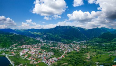 Evleri ve gölü olan küçük Bulgar kasabası Smolyan bulutların altında bitki örtüsü ve güneş ışınlarıyla kaplı. Rodop Dağları. Panorama, üst manzara