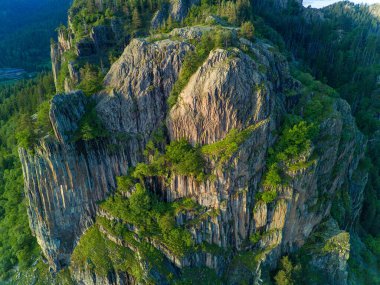 Rodop dağları vadisinde bitki örtüsüyle yüksek dağın kayalık zirvesi ve geniş bulutlu gökyüzünün arka planına karşı ormanlar.