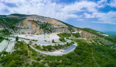 Düşük dağın yamacında, ormanları ve bulutlu gökyüzü olan Rodop Dağları 'nın bitkisel vadisinde modern teknolojinin yardımıyla madencilik. Panorama, üst manzara
