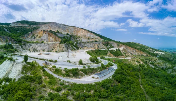 Düşük dağın yamacında, ormanları ve bulutlu gökyüzü olan Rodop Dağları 'nın bitkisel vadisinde modern teknolojinin yardımıyla madencilik. Panorama, üst manzara