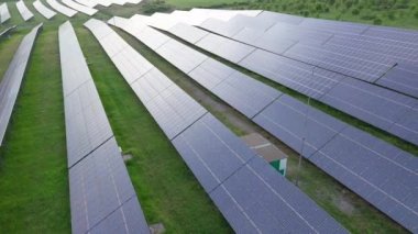 Modern eco-friendly large solar panels to generate energy from suns rays are installed in endless meadows with green grass, under a clear blue sky with bright warm spring sun. UHD 4K video realtime