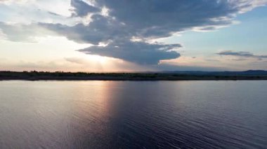 Boundless calm Black Sea with cool water reflecting light extends beyond the horizon, under colored sky with white volatile clouds and a bright dawn warm spring sun. UHD 4K video realtime