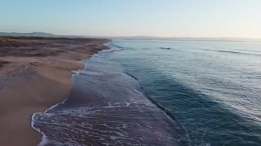 Sakin mavi uçsuz bucaksız Karadeniz, ışığı yansıtan soğuk su ve yakındaki kumlu boş kumsal, bulutlu renkli gökyüzüne karşı beyaz bulutlar ve parlak şafak güneşi. UHD 4K video gerçek zamanlı