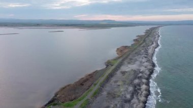 Kuşlar, kumsalın kuru kumla kaplı dar ve sessiz sahil manzarası ve Karadeniz 'in turkuaz körfezi ve akşam güneşinde açık mavi gökyüzünün altında küçük göl taşlarıyla yıkanmış taşlar. UHD 4K video gerçek zamanlı