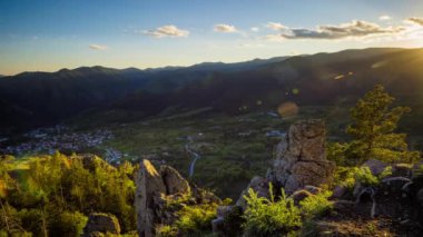 View from high rock to old village Smolyan with green meadows for cattle walking and houses, between mountain range of Rhodope Mountains sheltered by spruce forests. UHD 4K video footage timelaps