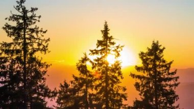 A mountain valley with mountain peaks of the Rhodope Mountains covered with dense spruce dark forests is shaded under a cloudy evening sunset bright sunny sky. UHD 4K video timelaps