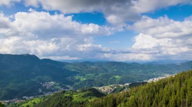 View from high rock to old village Smolyan with green meadows for cattle walking and houses, between mountain range of Rhodope Mountains sheltered by spruce forests. UHD 4K video footage timelaps
