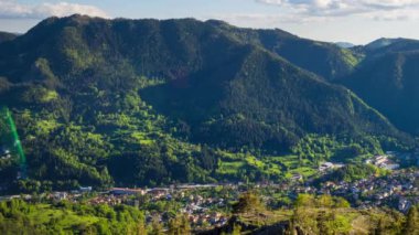 View from high rock to old village Smolyan with green meadows for cattle walking and houses, between mountain range of Rhodope Mountains sheltered by spruce forests. UHD 4K video footage timelaps