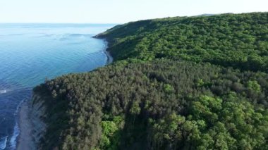 Yaz tatilleri için otelleri ve hanları olan küçük bir tatil köyü yeşil bitki örtüsü ile kayalık ve keskin uçurumlar üzerinde, açık mavi gökyüzüne karşı vahşi Karadeniz üzerinde. UHD 4K video gerçek zamanlı