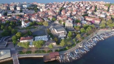 Bulgaristan 'ın kayalık yarımadasında bulunan ve büyük mavi, tuzlu Karadeniz tarafından turlanan küçük ve yoğun nüfuslu Pomorie kasabasına kuş bakışı bir bakış. UHD 4K video gerçek zamanlı