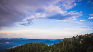 Green spring mountain valley sheltered by vegetation and spruce dark forests with small old village Smolyan, with grassy meadows where hungry motley sheep graze. UHD 8K video timelaps