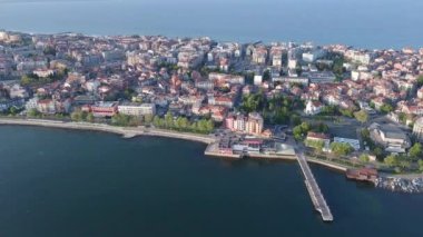 Bulgaristan 'ın kayalık yarımadasında bulunan ve büyük mavi, tuzlu Karadeniz tarafından turlanan küçük ve yoğun nüfuslu Pomorie kasabasına kuş bakışı bir bakış. UHD 4K video gerçek zamanlı