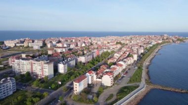 Bulgaristan 'ın kayalık yarımadasında bulunan ve büyük mavi, tuzlu Karadeniz tarafından turlanan küçük ve yoğun nüfuslu Pomorie kasabasına kuş bakışı bir bakış. UHD 4K video gerçek zamanlı
