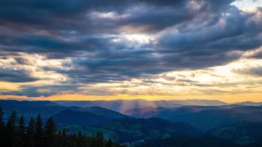 Cloudy weather over low hills covered with spruce evergreen forests in Rhodope Mountains against backdrop of sunset sky, and mystical thick white fog between mountain ranges. UHD 4K video timelaps