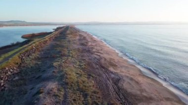 Kuşlar, kumsalın kuru kumla kaplı dar ve sessiz sahil manzarası ve Karadeniz 'in turkuaz körfezi ve akşam güneşinde açık mavi gökyüzünün altında küçük göl taşlarıyla yıkanmış taşlar. UHD 4K video gerçek zamanlı