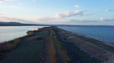 Kuşlar, kumsalın kuru kumla kaplı dar ve sessiz sahil manzarası ve Karadeniz 'in turkuaz körfezi ve akşam güneşinde açık mavi gökyüzünün altında küçük göl taşlarıyla yıkanmış taşlar. UHD 4K video gerçek zamanlı