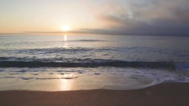 Calm blue boundless Black Sea with cool water reflecting light and sandy wild empty beach nearby, against cloudy colored sky with white clouds and bright dawn sun. UHD 8K video timelaps