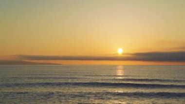 Calm blue boundless Black Sea with cool water reflecting light and sandy wild empty beach nearby, against cloudy colored sky with white clouds and bright dawn sun. UHD 8K video timelaps