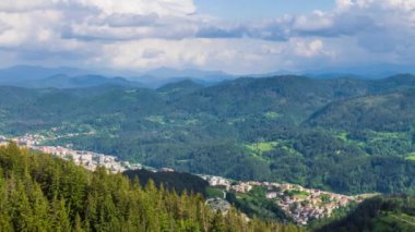 View from high rock to old village Smolyan with green meadows for cattle walking and houses, between mountain range of Rhodope Mountains sheltered by spruce forests. UHD 4K video footage timelaps