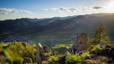 View from high rock to old village Smolyan with green meadows for cattle walking and houses, between mountain range of Rhodope Mountains sheltered by spruce forests. UHD 8K video footage timelaps