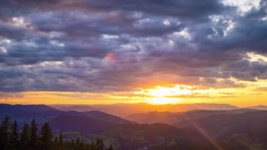 Cloudy weather over low hills covered with spruce evergreen forests in Rhodope Mountains against backdrop of sunset sky, and mystical thick white fog between mountain ranges. UHD 8K video timelaps