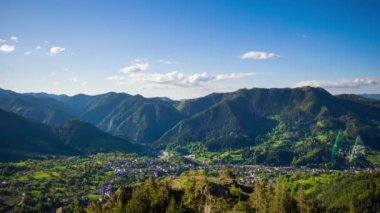 View from high rock to old village Smolyan with green meadows for cattle walking and houses, between mountain range of Rhodope Mountains sheltered by spruce forests. UHD 8K video footage timelaps