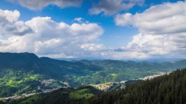 View from high rock to old village Smolyan with green meadows for cattle walking and houses, between mountain range of Rhodope Mountains sheltered by spruce forests. UHD 8K video footage timelaps