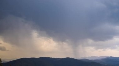 Mighty overcast large thick clouds covered the daytime sky over the mountain valley of the Rhodope Mountains with spruce dark forests and empty wild meadows. UHD 4K video timelaps