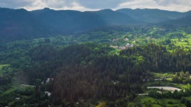 View from high rock to old village Smolyan with green meadows for cattle walking and houses, between mountain range of Rhodope Mountains sheltered by spruce forests. UHD 4K video footage timelaps
