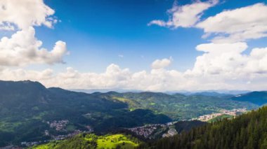 View from high rock to old village Smolyan with green meadows for cattle walking and houses, between mountain range of Rhodope Mountains sheltered by spruce forests. UHD 4K video footage timelaps