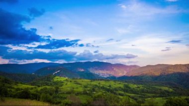 Multicolored evening sky with small clouds and sunny sunset light over the mountain valley of the Rhodope Mountains with a small lonely intermountain village. UHD 4K video timelaps