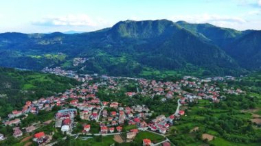 Yüksek kayadan eski köy kasabası Smolyan 'a sığır yürüyüşü için yeşil çayırlar ve dağ sırasındaki Rodop Dağları arasında ladin ormanlarıyla korunan evler. UHD 4K video gerçek zamanlı