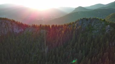 High rocky wild mountain range of Rhodope Mountains covered with green vegetation, against backdrop of mountain valley covered with dense dark spruce forests and blue cloudy sky. UHD 4K video realtime