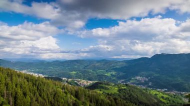 View from high rock to old village Smolyan with green meadows for cattle walking and houses, between mountain range of Rhodope Mountains sheltered by spruce forests. UHD 4K video footage timelaps