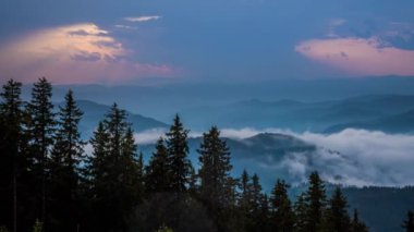 Cloudy weather over low hills covered with spruce evergreen forests in Rhodope Mountains against backdrop of dark sky, and mystical thick white fog between mountain ranges. UHD 4K video timelaps