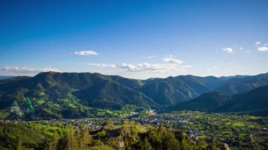 View from high rock to old village Smolyan with green meadows for cattle walking and houses, between mountain range of Rhodope Mountains sheltered by spruce forests. UHD 8K video footage timelaps